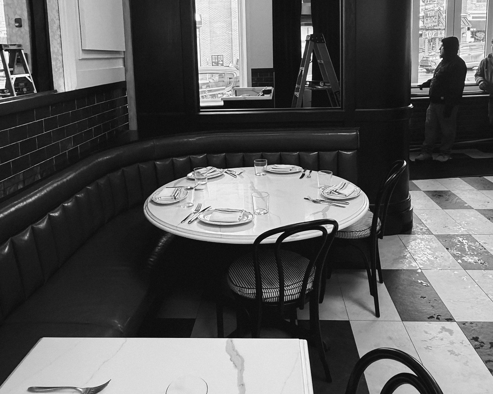 A green banquette booth with tables set for service
