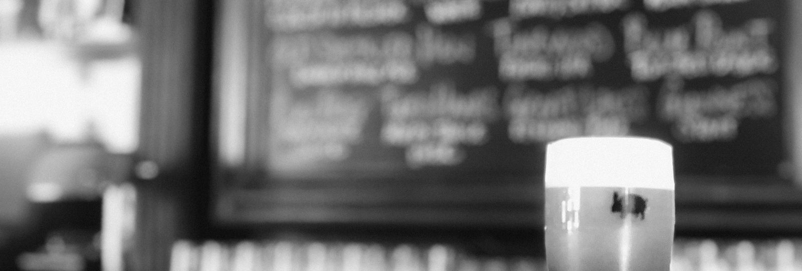 A fresh pint on the bar under a chalkboard draft list