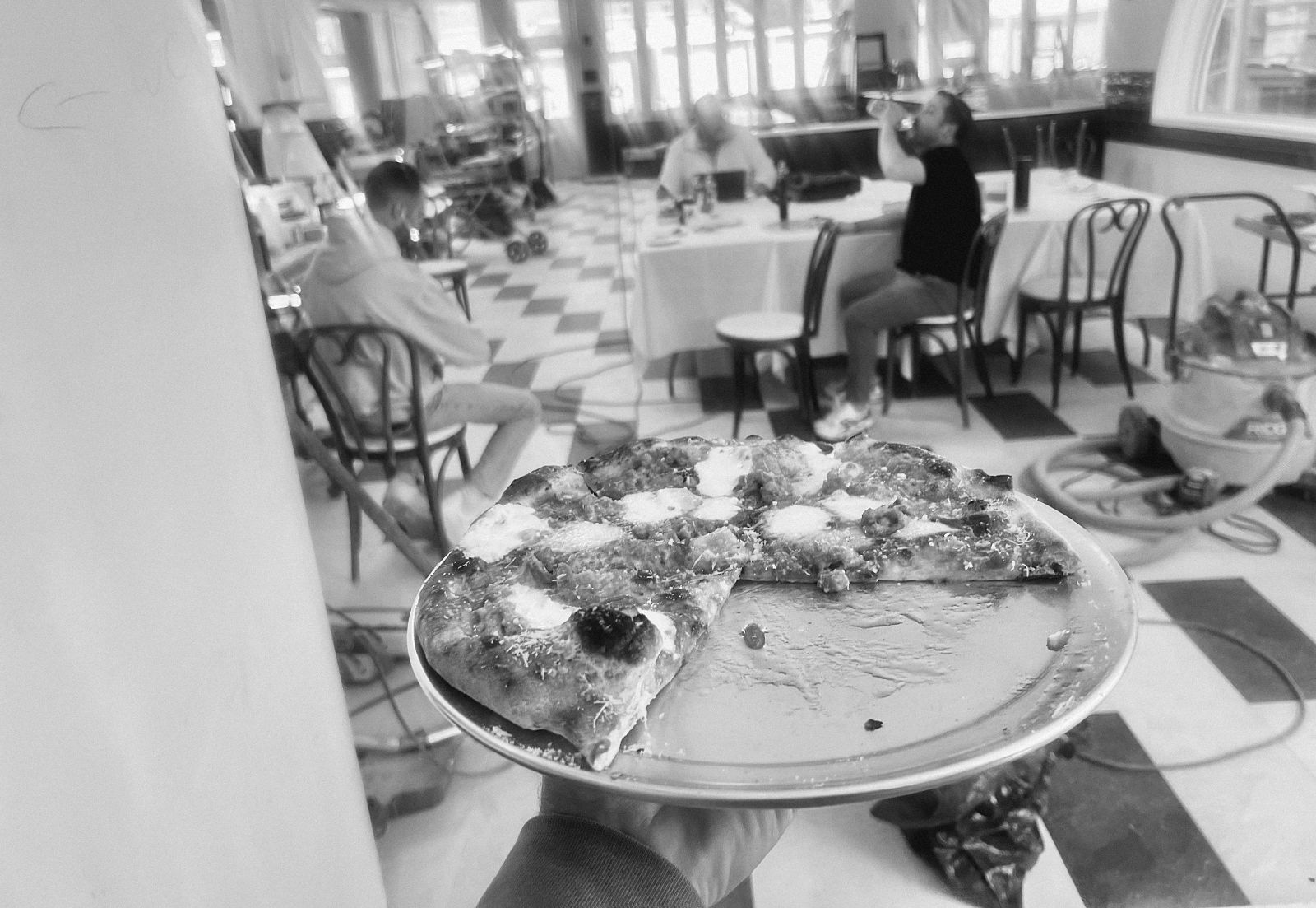 A pizza carried to the table at a pre-opening tasting