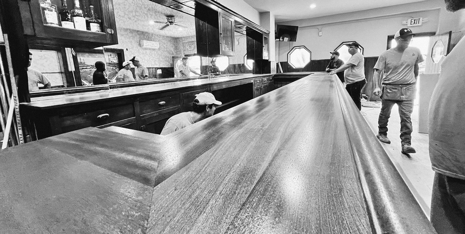 A mahogany bar top being installed during a build-out