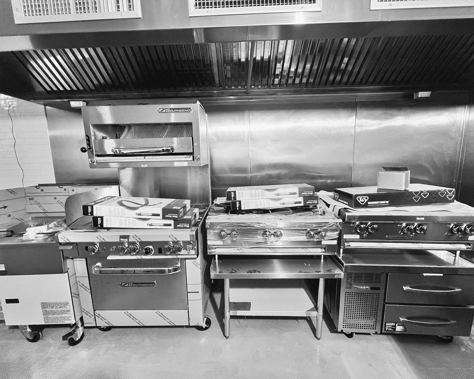 New kitchen equipment, still in its wrapping, lined up under the hood