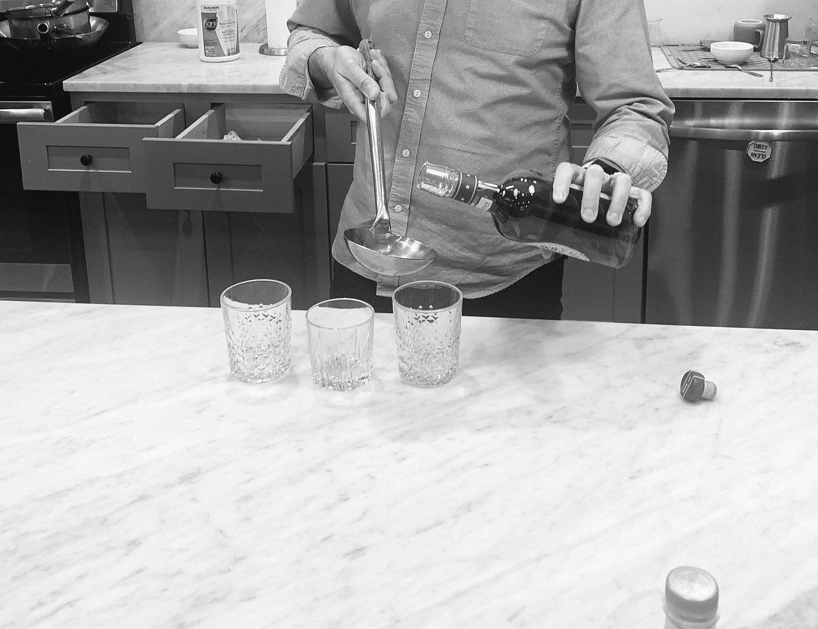 A spirit being ladled into glasses at a marble counter