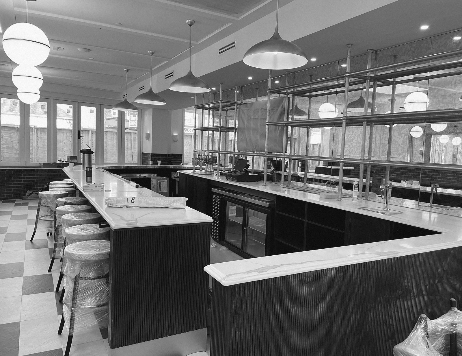 A finished bar with brass shelving and pendant lights